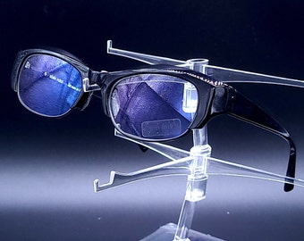 May include: Black framed glasses with blue tinted lenses on a clear plastic display stand.