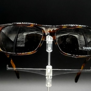 Puede incluir: Gafas de sol de carey con lentes oscuros y la palabra "SHARCK" impresa en la lente derecha.