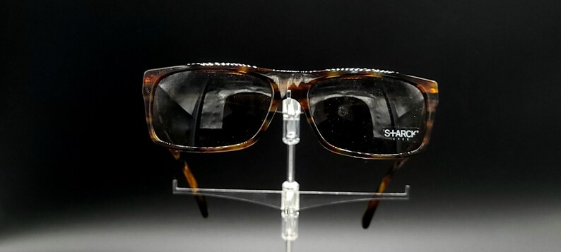 Puede incluir: Gafas de sol de carey con lentes oscuros y la palabra "SHARCK" impresa en la lente derecha.