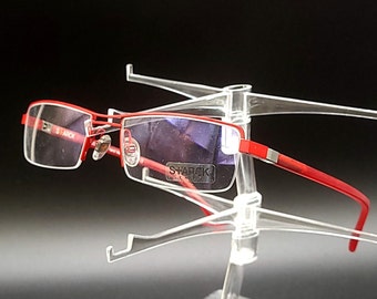 May include: Red metal frame glasses with clear lenses and a blue tint. The glasses are on a clear plastic display stand. The brand name "SHARICK" is visible on the glasses.