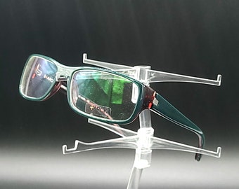 May include: Green and brown rectangular eyeglasses with clear lenses on a clear plastic display stand.