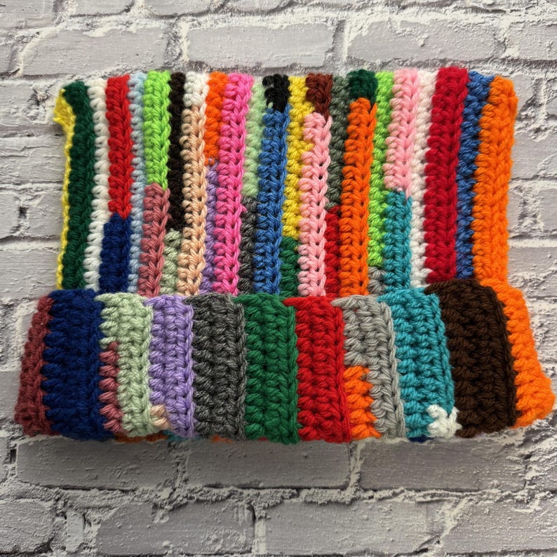 Pu&ograve; includere: Un cappello all'uncinetto fatto a mano con un design patchwork. Il cappello presenta strisce verticali in una variet&agrave; di colori, tra cui rosso, verde, rosa, blu e arancione. Il cappello &egrave; realizzato in filato morbido e ha un bordo ripiegato, creando un accessorio vivace.