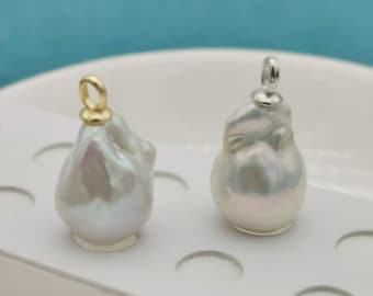 Pode incluir: Dois pingentes de pérola barroca branca com argolas de ouro e prata. As pérolas são de forma irregular e têm um alto brilho.