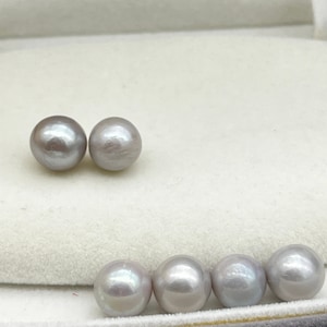 Könnte beinhalten: Sechs runde, glatte, graue Perlen in einer weißen Schachtel. Die Perlen sind in zwei Reihen angeordnet, mit drei Perlen in jeder Reihe.