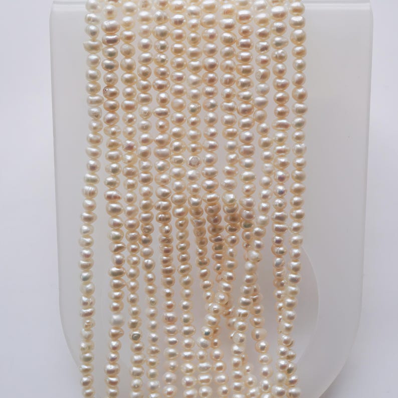 May include: A strand of white freshwater pearls, approximately 5-6mm in size. The pearls are round and have a smooth, lustrous finish.
