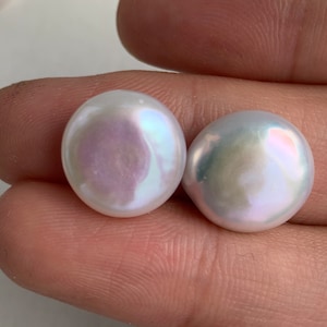 May include: Two large, white, round pearls with an iridescent sheen.
