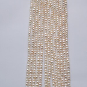 May include: A strand of white freshwater pearls, approximately 4-5mm in size. The pearls are strung on a thin thread and are ready to be used for jewelry making.