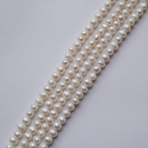 May include: A strand of white pearls, strung together in a long, elegant necklace. The pearls are smooth and lustrous, with a subtle sheen.