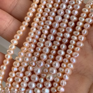 Może przedstawiać: Sznur jasnoróżowych pereł słodkowodnych. Perły są okrągłe i mają delikatny, tęczowy połysk.