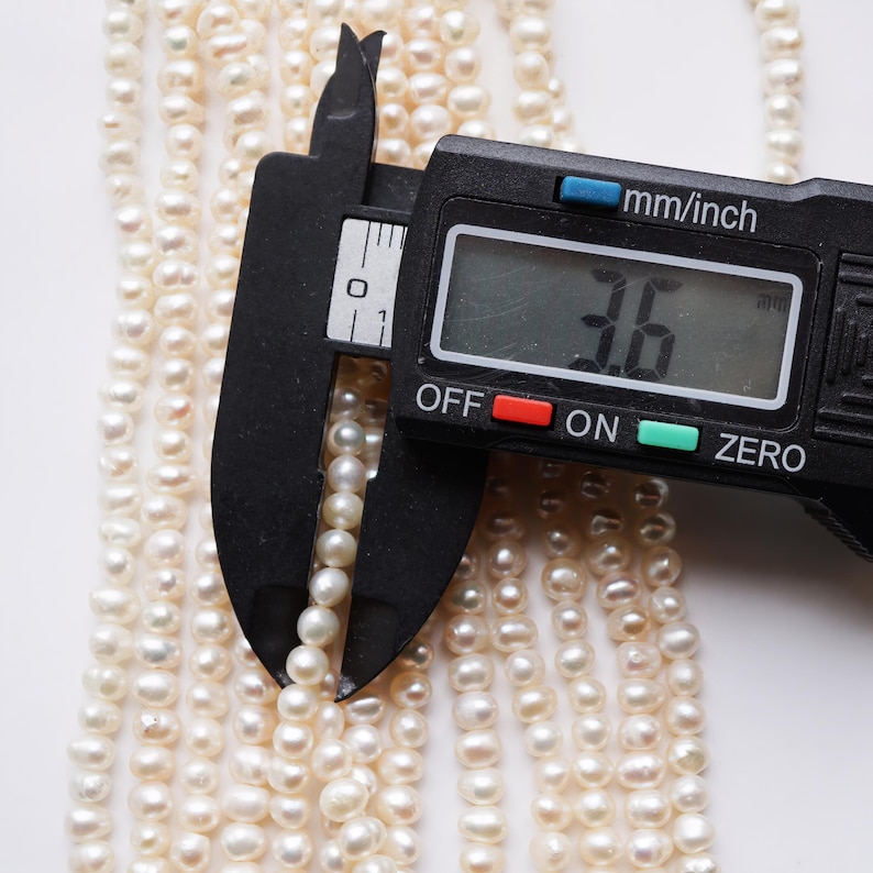 May include: A close-up of a digital caliper measuring a strand of white pearls. The caliper reads 3.6 mm.