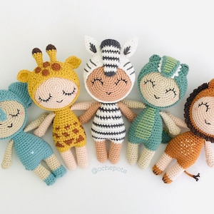 May include: Five crocheted stuffed toys dressed as different animals. The animals are a giraffe, zebra, dinosaur, elephant, and lion. The animals are all lying down with their eyes closed. The animals are all made with different coloured yarn. The animals are all about 10 inches tall.
