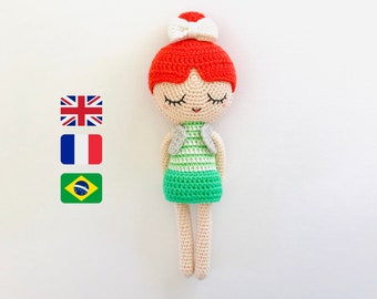 May include: A crocheted doll with red hair, a white bow, and a green and white striped dress. The doll has closed eyes and a smiling mouth.