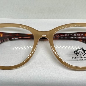 May include: Tan-colored eyeglasses with a rounded square frame and tortoise-shell arms. The glasses have a small logo of a monkey wearing glasses. The frame size is 50-17-145.