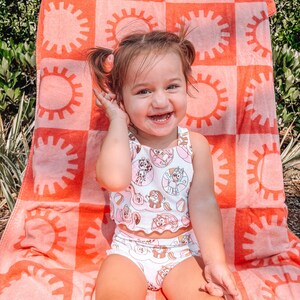 May include: A white ceramic mug with a black handle and the text "But First, Coffee" in a bold, black font. The mug is set against a blurred background, suggesting a cosy setting.