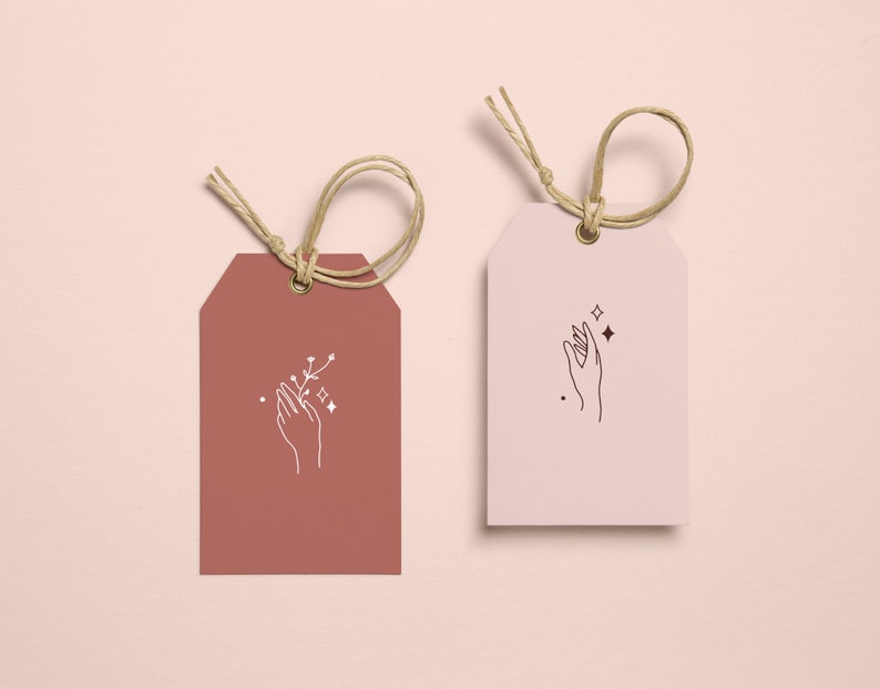 May include: Two gift tags with a hand holding a small branch with stars. The tag on the left is brown and the tag on the right is white.