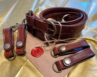 May include: A set of brown leather straps with metal buckles and rings. The straps are tied together with twine and have a wax seal with a fleur-de-lis design.