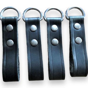 May include: Four black leather belt loops with silver metal rings and two silver metal rivets each.