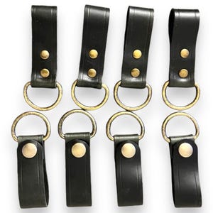 May include: Five black leather keychains with two brass rings each. The keychains have a brass button on the bottom.