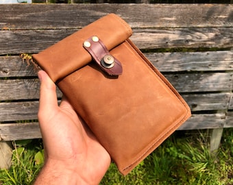 May include: A brown leather pouch with a flap closure and a brass button. The pouch has a brown leather strap with brass rivets.