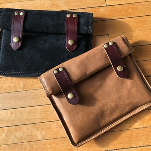 May include: Two leather pouches with brown leather straps and brass buckles. One pouch is black and the other is brown.