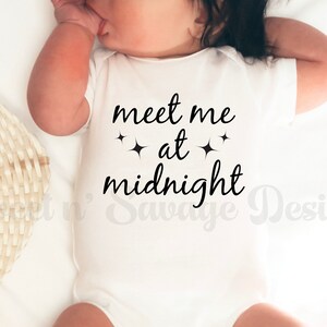 May include: White baby onesie with black text that reads "meet me at midnight" with two small stars on either side of the word "at".