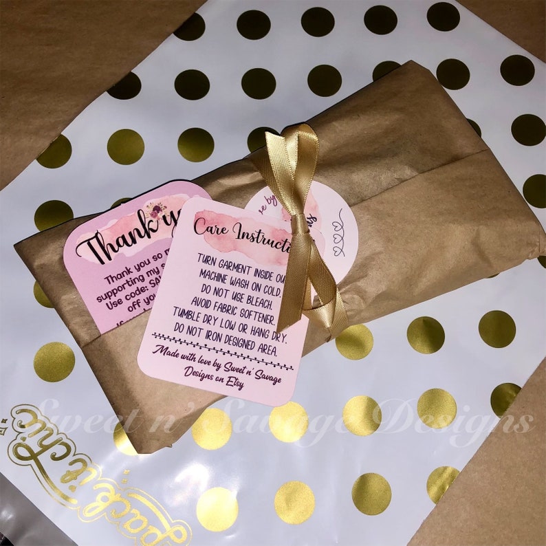 May include: A brown paper package tied with a gold ribbon and two pink and white cards. The cards have the text "Thank you so much for supporting my small business! Use code: SAVE15 off your order!" and "Care Instructions: Turn garment inside out. Machine wash on cold. Do not use bleach. Avoid fabric softener. Tumble dry low or hang dry. Do not iron designed area. Made with love by Sweet n' Savage Designs on Etsy."