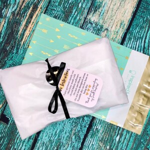 May include: A rectangular package wrapped in white tissue paper, tied with a black ribbon and a tag that reads: Care Instructions. Turn garment inside out. Machine wash cold. Avoid fabric softener. Do not use bleach. Do not iron designed areas. Tumble dry on low heat or hang dry. Thank you for supporting my small business!