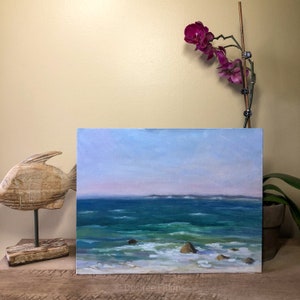 Könnte beinhalten: Ein Gemälde, das eine Meereslandschaft mit blauem Himmel und grünem Wasser zeigt. Das Wasser ist unruhig und es gibt Schaumkronen auf den Wellen. Das Gemälde ist gerahmt und hängt an einer Wand.