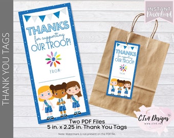 Könnte beinhalten: Zwei bedruckbare Dankeschön-Etiketten mit einem blauen und weißen Design, einer bunten Blume und drei Mädchen in blauen und weißen Scout-Uniformen. Der Text auf den Etiketten lautet "Danke für die Unterstützung unserer Gruppe!" und "Von:".