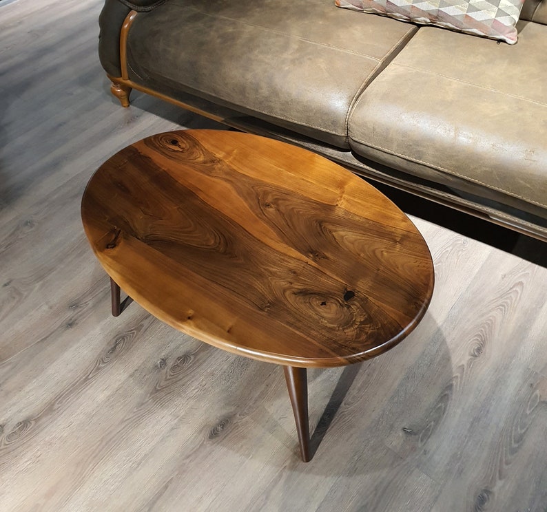 May include: A wooden oval-shaped coffee table with a dark brown wood grain finish and black metal legs.