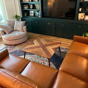 May include: A brown leather sectional sofa with a wooden coffee table in a living room with a dark green built-in entertainment center and shelves.