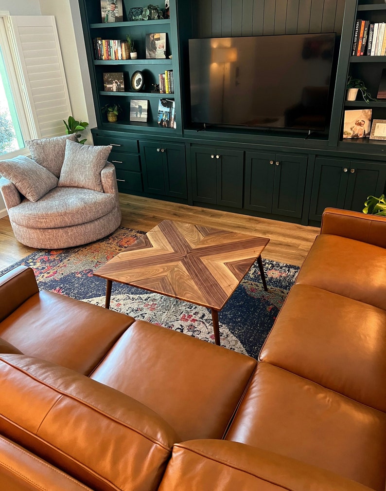 May include: A brown leather sectional sofa with a wooden coffee table in a living room with a dark green built-in entertainment center and shelves.