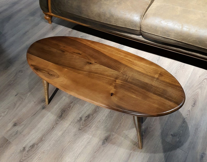 May include: A wooden oval coffee table with a dark brown stain. The table has a simple design with four legs.