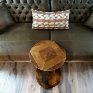May include: A brown leather sofa with a patterned pillow and a round wooden side table with a black metal base.