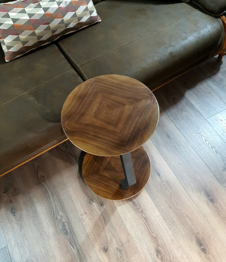 May include: A two-tiered wooden side table with a dark brown wood finish and a black metal base. The table has a round top and a lower shelf.