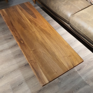May include: A rectangular wooden coffee table with a natural wood finish. The table top has a smooth surface and a light brown color.