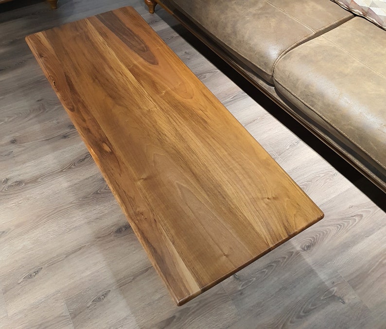 May include: A rectangular wooden coffee table with a natural wood finish. The table top has a smooth surface and a light brown color.