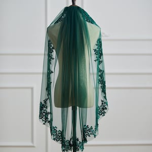 May include: A green bridal veil with a lace trim. The veil is made of tulle and has a scalloped edge.