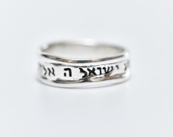 May include: A silver ring with Hebrew writing engraved around the band.