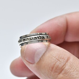 Puede incluir: Un anillo giratorio de plata con texto hebreo grabado en la banda.