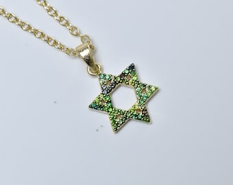 May include: A gold chain necklace with a green and blue star of David pendant. The pendant is covered in small, sparkling stones.
