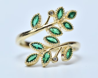 May include: A gold ring with a delicate design of green leaves and small clear stones.