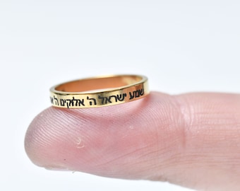 Könnte beinhalten: Ein dünner Goldring mit hebräischer Schrift, die auf der Außenseite eingraviert ist.