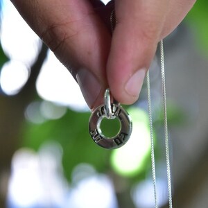 May include: A silver chain necklace with a round pendant featuring Hebrew lettering.