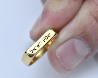 May include: A gold ring with a square band engraved with the Hebrew words "אהבה עמוקה" which translates to "deep love".