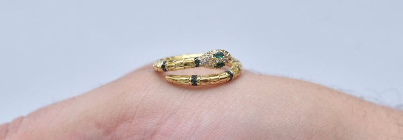 May include: A gold snake ring with black and green enamel accents and clear cubic zirconia stones.