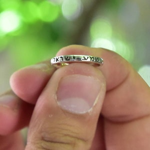 May include: A silver ring with Hebrew lettering inscribed on the band.