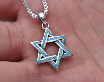 May include: A silver Star of David pendant necklace with blue opal inlay. The pendant is on a silver chain.