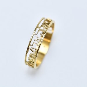 May include: A gold-coloured ring with a double-layered band featuring Hebrew lettering.