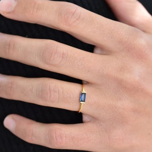 May include: A gold ring with a blue rectangular gemstone.